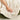 Person holding a fluffy white blanket with a visible brand label on a soft surface.