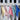 Five colorful dog bandanas hanging on a wooden rack with a neutral background