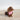 Small brown dog wearing a pink bandana on a concrete surface with a white wall background