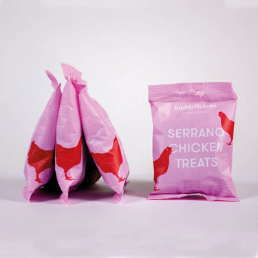 Pink packages of Serrano Chicken treats on a white background